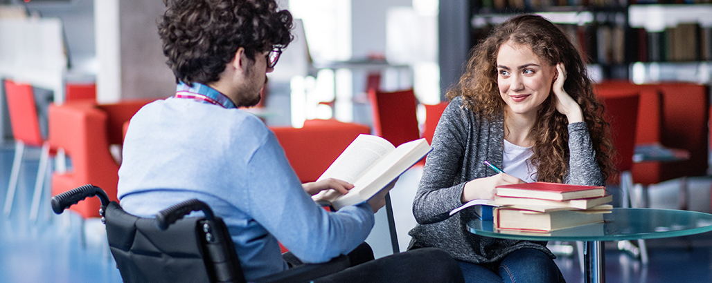 Male and female students supporting each other in a library.